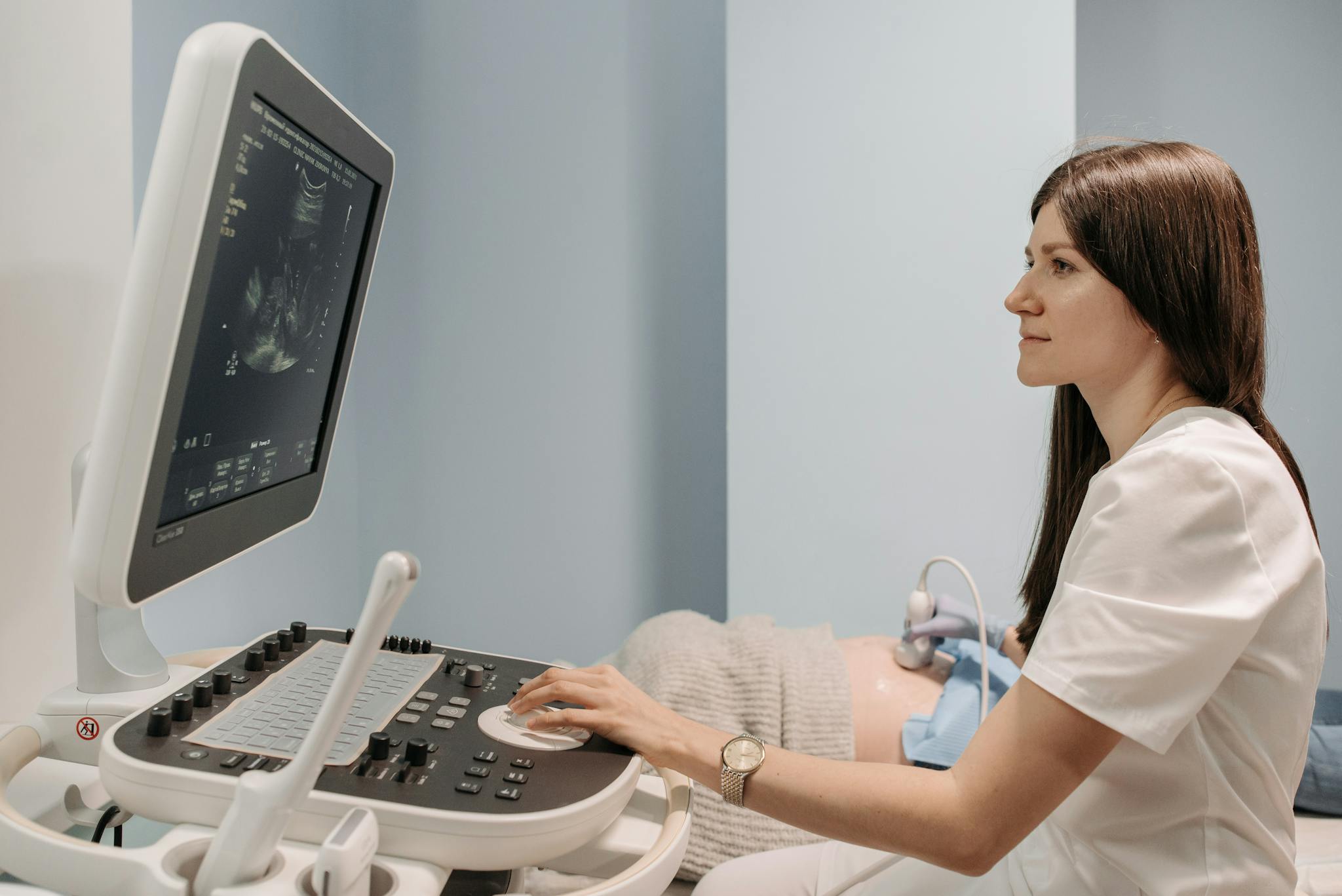 Jordemoder scanner en gravid kvindes mave med ultralyd for at vise babyen.