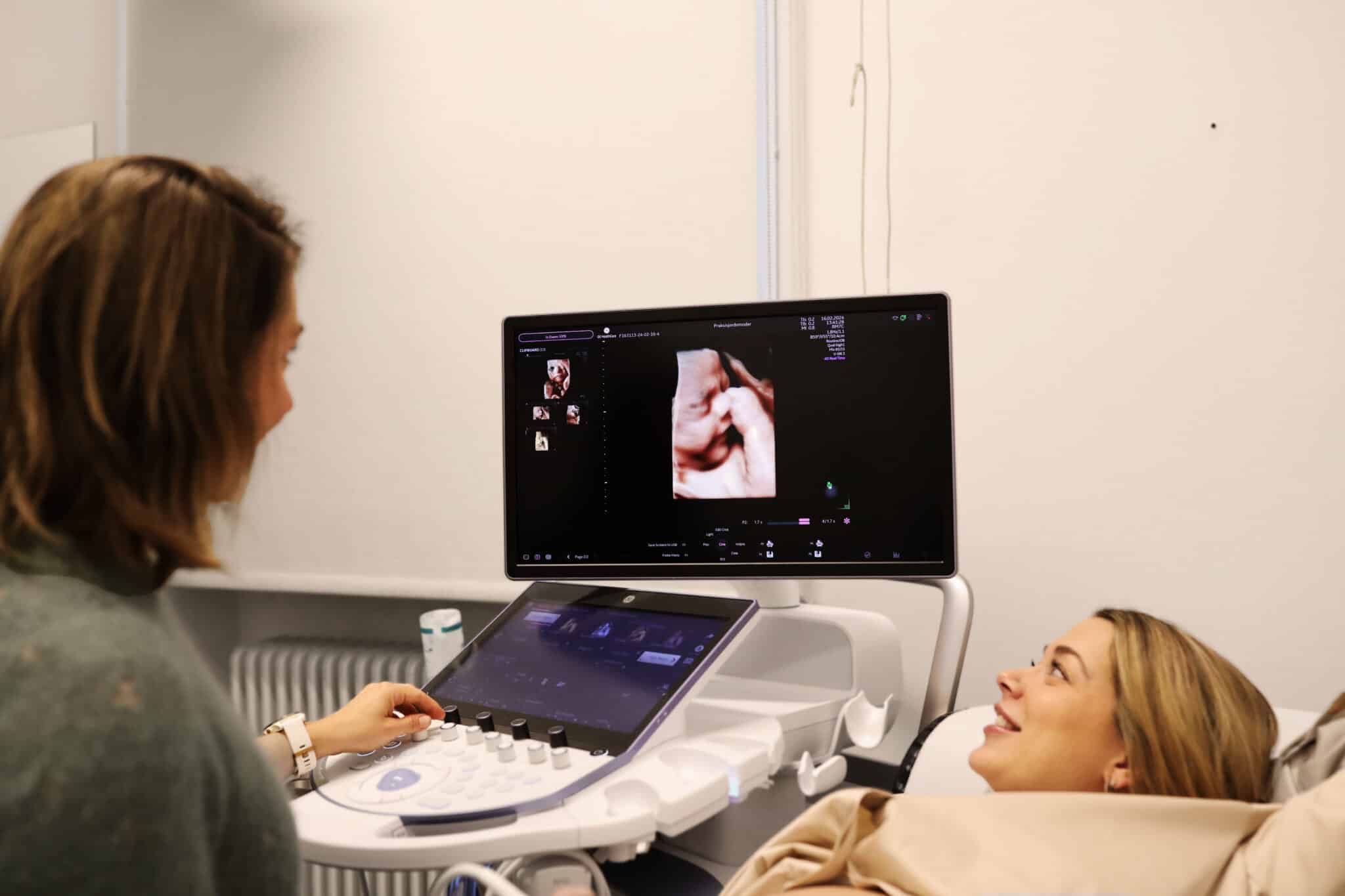 Jordemoder scanner en gravid kvinde, der ser på 3D ultralydsbillede af foster.
